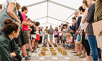 A group of students at the BASEhabitat Summer School examine the consistency of earth blocks made with different recipes